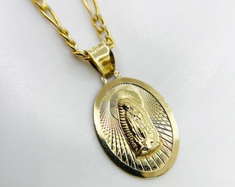 May include: A gold chain necklace with a pendant featuring an oval-shaped image of the Virgin Mary. The pendant has a detailed design with a textured background and a raised image of the Virgin Mary.
