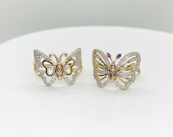 May include: Two gold butterfly rings with clear stones. One ring has a pink stone in the center of the butterfly.