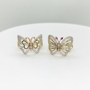 May include: Two gold butterfly rings with clear stones. One ring has a pink stone in the center of the butterfly.