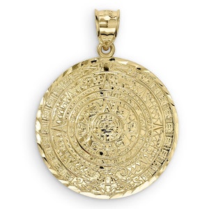 May include: A gold pendant featuring a detailed depiction of the Aztec calendar, also known as the Sun Stone. The pendant is circular and has a textured surface.
