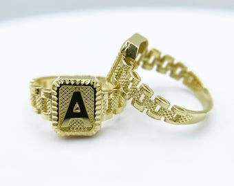 May include: Two gold rings, one with a square-shaped initial "A" and the other with a chain-link design.