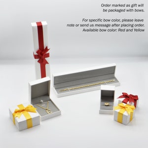 Jewelry boxes with varied bows a tall box with a red bow, another with a yellow bow and an "E" necklace a long box with a gold bracelet & two small boxes with yellow & red bows. Orders marked as gifts include bows with red & yellow options available.