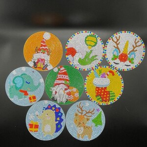May include: Seven round, colorful, sparkly, Christmas-themed ornaments with various designs, including a reindeer, a stocking, a gnome, a hedgehog, an elephant, a unicorn, and a Santa Claus.