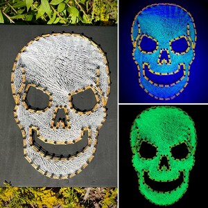 May include: A skull string art piece with white string and gold accents on a black background. Additional images show the skull glowing blue and green. The skull has eye sockets, a nose, and a smiling mouth.