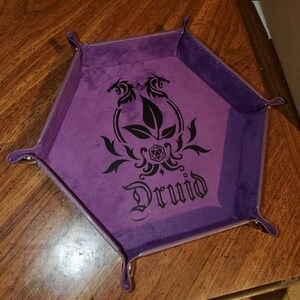 May include: Purple velvet dice tray with a black design of two dragons flanking a leaf and a die with the word "Druid" below.