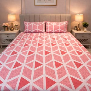 May include: A bed featuring a pink and white geometric patterned duvet cover and two matching pillowcases. The pattern is made up of diamond and triangle shapes. The room has a neutral colour scheme with bedside tables and lamps.