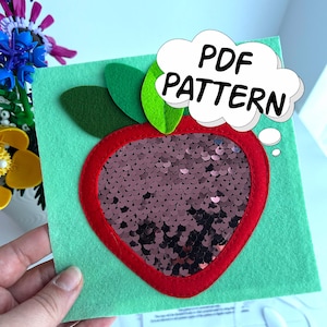 Puede incluir: Un proyecto de manualidades de fieltro con un cuadrado verde con un contorno de manzana roja. El centro de la manzana está relleno de lentejuelas marrones. Hojas verdes de fieltro y las palabras "PDF PATTERN" en una burbuja completan el diseño.