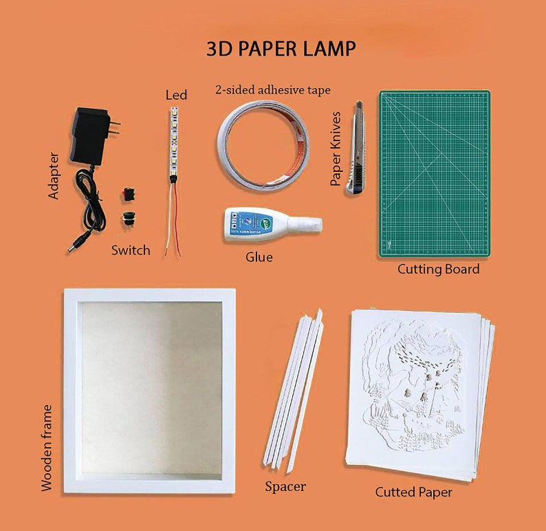 Op de afbeelding: Een 3D-papierlampenset met alle benodigde materialen om een ​​aangepaste lamp te maken. De set bevat een houten frame, een vel gesneden papier, afstandhouders, lijm, een snijmat, een hobbymes, LED-verlichting, een schakelaar, een adapter en dubbelzijdig plakband.