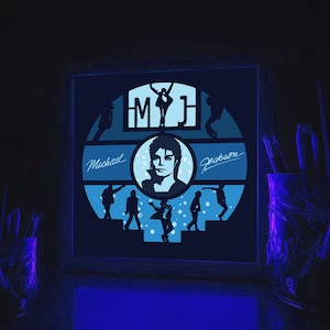 K&ouml;nnte beinhalten: Ein gerahmtes, leuchtend blaues und wei&szlig;es, im Dunkeln leuchtendes Wandbild mit einer Silhouette von Michael Jackson mit dem Text "MJ" und "Michael Jackson".