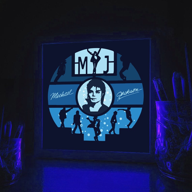 K&ouml;nnte beinhalten: Ein gerahmtes, leuchtend blaues und wei&szlig;es, im Dunkeln leuchtendes Wandbild mit einer Silhouette von Michael Jackson mit dem Text "MJ" und "Michael Jackson".