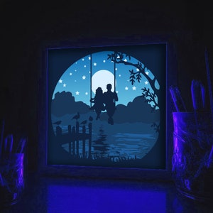 May include: A silhouette of a couple sitting on a swing under a starry night sky. The scene is illuminated by a full moon and features a wooden dock with birds perched on the railing.