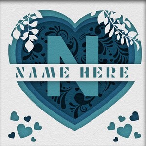 Op de afbeelding: Een blauw hart van papier met een wit bloemmotief en de letter N in het midden. De tekst "NAME HERE" staat in het wit over het midden van het hart.