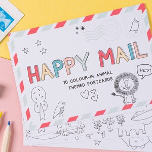 May include: A set of 10 blank postcards featuring colour-in animal illustrations. The postcards are stacked and have a red and white striped border. The top postcard has the text "HAPPY MAIL" in colourful letters and the text "10 COLOUR-IN ANIMAL THEMED POSTCARDS".