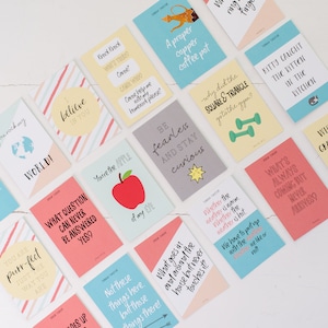 May include: A set of colourful cards with various phrases and illustrations. The cards feature a variety of themes, including food, animals, and inspirational quotes. The cards are printed on a white background with black text.
