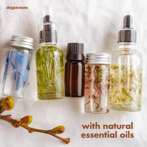 May include: Five glass bottles with clear liquid and natural ingredients inside. The bottles are labeled with the text "with natural essential oils".