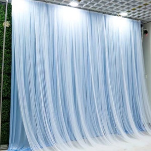Könnte beinhalten: Ein hellblauer, durchsichtiger Vorhang als Hintergrund mit weißem Hintergrund. Der Vorhang besteht aus vielen dünnen Stofffäden, die von einer Stange herabhängen.