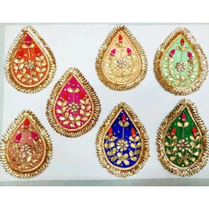 May include: Seven teardrop-shaped fabric embellishments with gold trim and embroidery. The embellishments are in various colors, including orange, pink, green, blue, and cream.