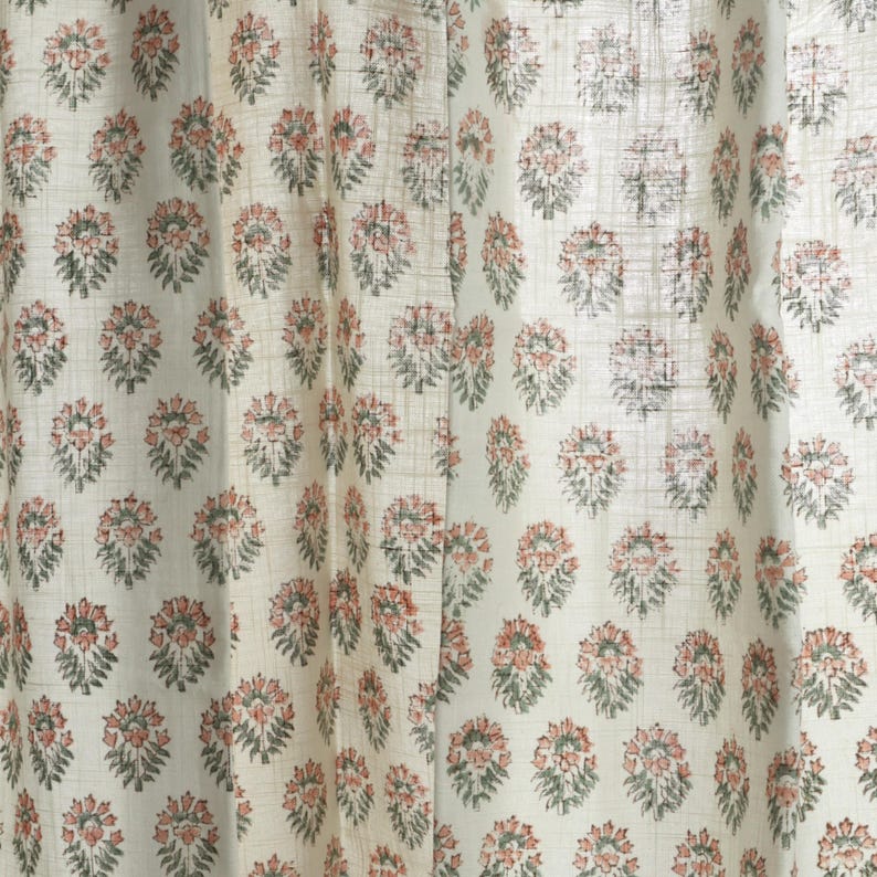 May include: White fabric with a repeating pattern of small, green and pink floral designs.