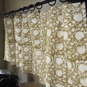 May include: A set of mustard yellow curtains with a white floral pattern. The curtains are hung on a black curtain rod.