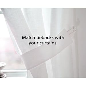 May include: White sheer curtains with a white tieback. The tieback is tied back to the curtain and the text "Match tiebacks with your curtains." is visible.