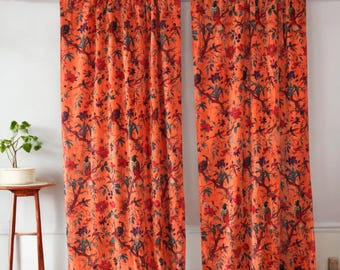 May include: A pair of orange velvet curtains with a floral and bird print. The curtains are hung on a white wall.