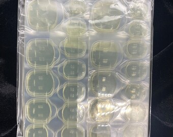 May include: A clear plastic sheet with multiple clear, round, and oval-shaped adhesive pads. The pads are arranged in rows and columns.