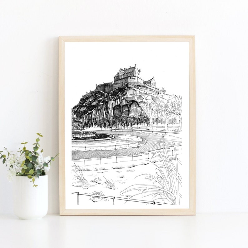 K&ouml;nnte beinhalten: Schwarz-Wei&szlig;-Zeichnung eines Schlosses auf einem H&uuml;gel, gerahmt in hellem Holz. Das Kunstwerk zeigt das Schloss, B&auml;ume und einen Brunnen im Vordergrund. Der Stil ist detailliert und illustrativ.