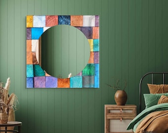 May include: A colorful square mirror with a round mirror in the center. The mirror is made of small squares of different colors, including blue, green, orange, and brown. The mirror is hanging on a green wall.