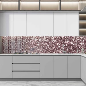 May include: A modern kitchen with white cabinets and a gray countertop. The backsplash is a mosaic of small, iridescent pink tiles.