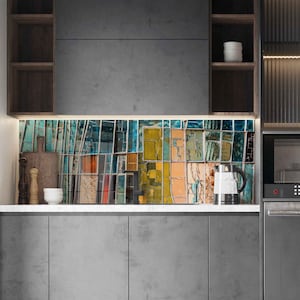 May include: A modern kitchen with gray cabinets and a colorful backsplash. The backsplash features a mosaic design with shades of blue, yellow, orange, and green. A stainless steel kettle and a cutting board are on the countertop.