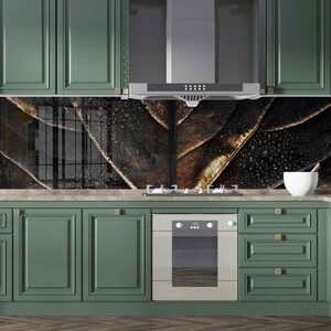 May include: A kitchen with green cabinets and a black and gold patterned backsplash. The backsplash features a design of overlapping leaves with a metallic gold finish. The kitchen also has a stainless steel oven and a white countertop.