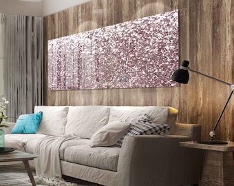 May include: A large, rectangular wall art piece with a glittery, pink and white design hangs above a beige sofa. The room features wood paneling, a black desk lamp, and a light-colored throw blanket.