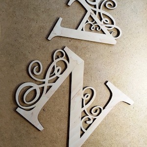 May include: Two wooden letters, N and Z, with decorative swirls cut out. The letters are light brown and have a natural wood grain.