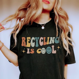 K&ouml;nnte beinhalten: Schwarzes T-Shirt mit dem Text "Recycling is Cool" in bunten Retro-Lettern und zwei Smiley-Gesichtern.
