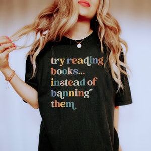 May include: A black t-shirt with the text "try reading books... instead of banning them" in colorful letters.