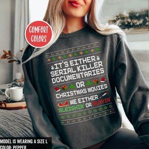 Peut inclure: Un sweat-shirt gris fonc&eacute; avec un motif de No&euml;l. Le texte sur le sweat-shirt est "It's either serial killer documentaries or Christmas movies. We either sleighin' or slayin'."