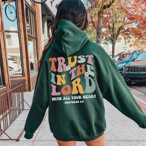 May include: Green hooded sweatshirt with the text "TRUST IN THE LORD WITH ALL YOUR HEART PROVERBS 3:5" in colorful retro lettering.