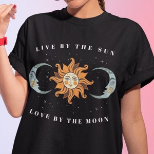 May include: Black t-shirt with a graphic of a sun and moon with the text "Live by the sun, love by the moon".