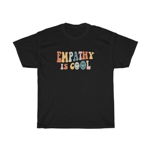May include: Black t-shirt with the text "EMPATHY IS COOL" in rainbow colours with smiley faces.