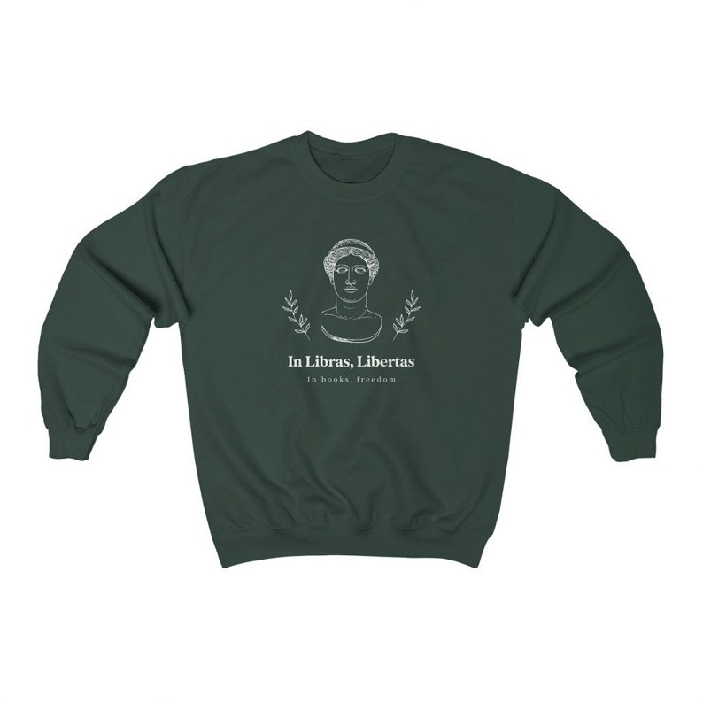May include: A dark green sweatshirt with a white graphic of a bust of a woman with a laurel wreath around her head. The text "In Libras, Libertas" is below the image, and the text "In books, freedom" is below that.
