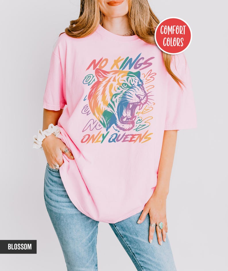 May include: A light pink t-shirt with the text "NO KINGS ONLY QUEENS" and a colorful tiger graphic. The shirt is labeled "Comfort Colors" and "Blossom".