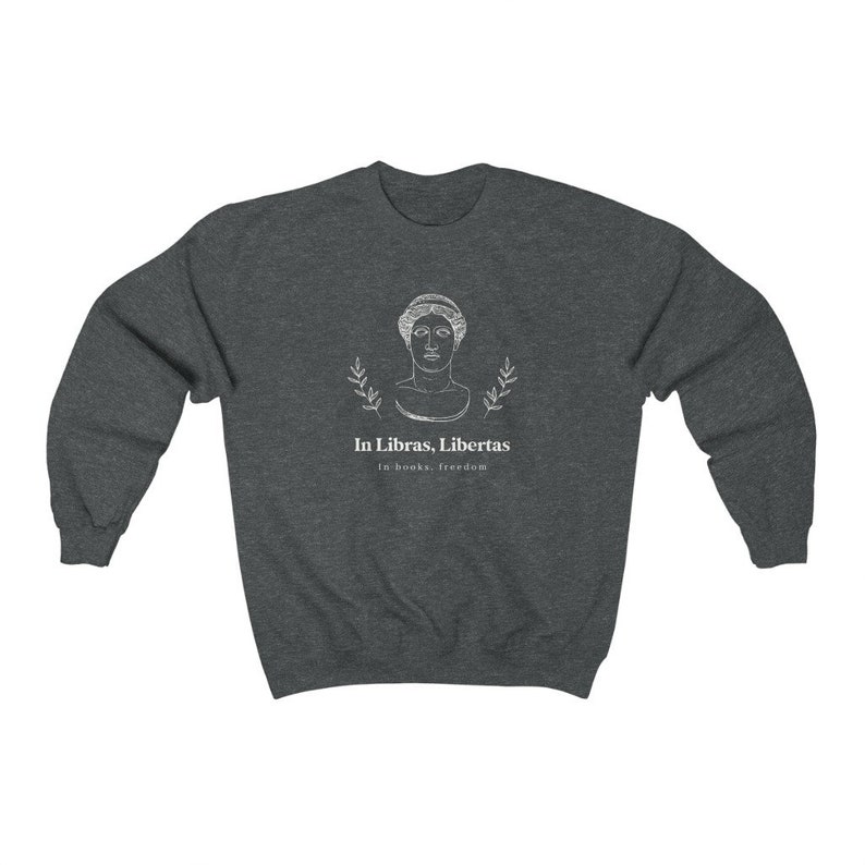 May include: A dark heather grey sweatshirt with a white graphic design featuring a bust of a woman with laurel branches and the text "In Libras, Libertas" and "In books, freedom".