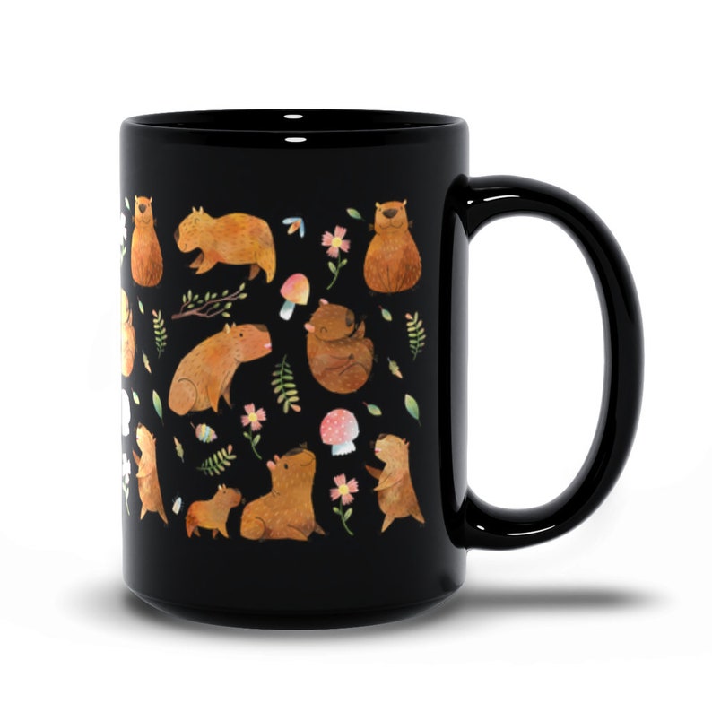 May include: Black ceramic coffee mug with a white design of capybaras, mushrooms, and flowers.