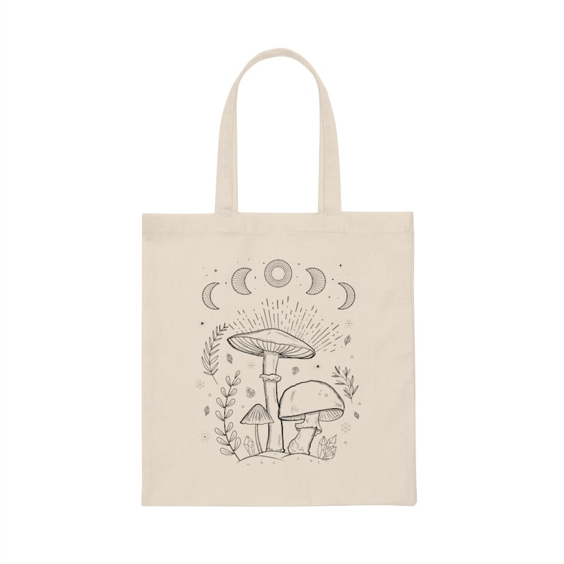 K&ouml;nnte beinhalten: Eine beige Tragetasche mit einer schwarz-wei&szlig;en Illustration von Pilzen und einem Halbmond-Design. Die Tasche hat einen schwarzen Griff.
