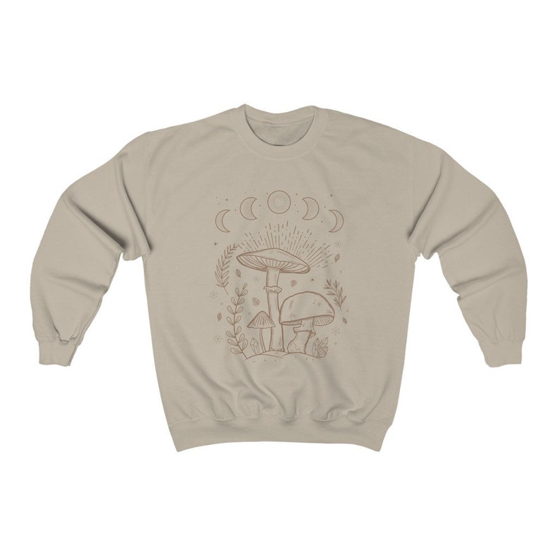 May include: A beige sweatshirt featuring a line drawing of mushrooms and a crescent moon design. The design is in a brown colour.