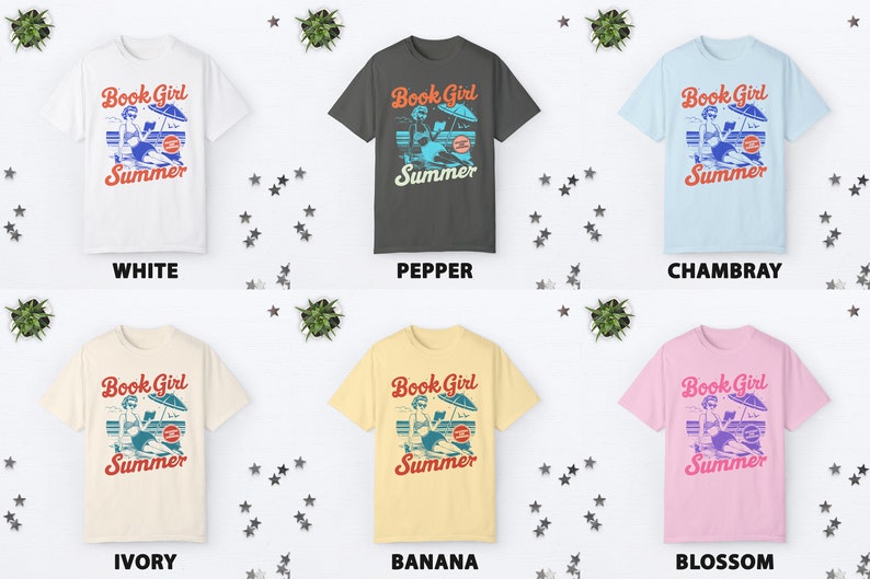 K&ouml;nnte beinhalten: Sechs T-Shirts in verschiedenen Farben mit einem Motiv einer Frau, die am Strand ein Buch liest, mit dem Text "Book Girl Summer". Die Farben sind Wei&szlig;, Pfeffer, Chambray, Elfenbein, Banane und Bl&uuml;te.