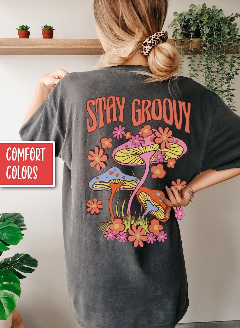 May include: A dark gray t-shirt with the text "STAY GROOVY" in orange and a retro design of mushrooms and flowers.