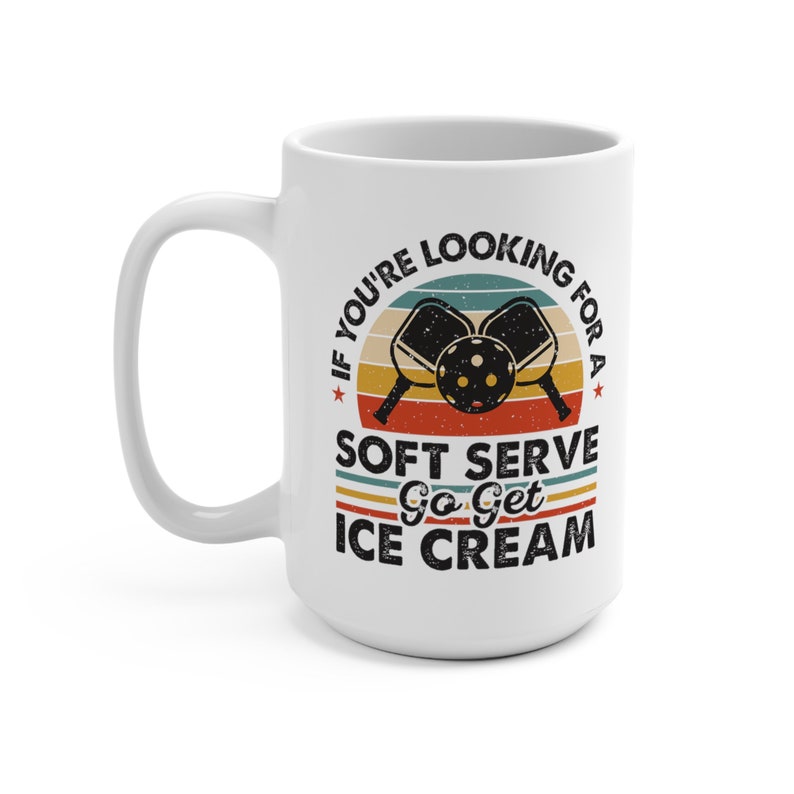 May include: White ceramic mug with a retro sunset design and the text "If you're looking for a soft serve go get ice cream". The design also includes two pickleball paddles and a ball.