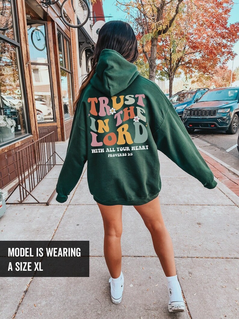 May include: Green hooded sweatshirt with the text "TRUST IN THE LORD WITH ALL YOUR HEART PROVERBS 3:5" in colorful retro lettering.