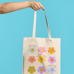 May include: A white canvas tote bag with colorful flower designs and the text "take it easy", "know your worth", and "only good vibes".